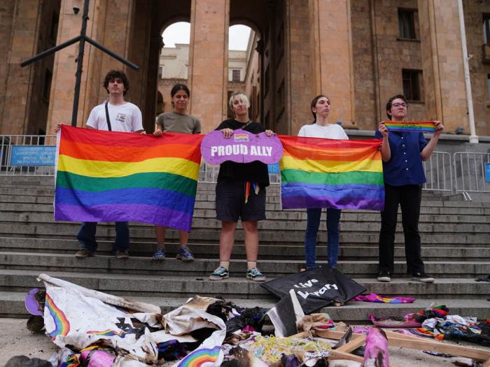 Tbilisi Pride organizers held up rainbow flags and broken signs on the steps of Georgia's Parliament July 9, 2023, as they stood above remnants of destroyed Pride festival stuff gathered after thousands of anti-gay protesters attacked the July 8 festival in Georgia's capital. Photo: Courtesy Tbilisi Pride/Facebook 
