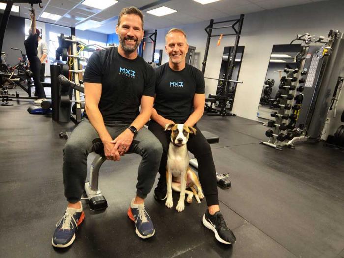 Glenn Shope, left, and his husband, Dave Karraker, recently opened their new MX3 Fitness location in Noe Valley and are joined by their rescue dog Liz Lemon Claiborne Taylor Colton Smith. Photo: Rick Gerharter